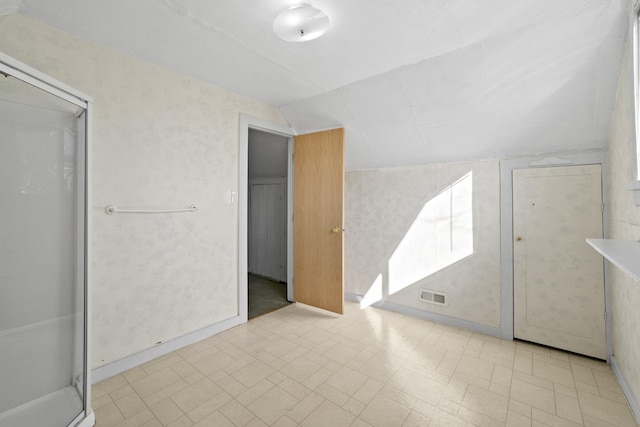 interior space featuring baseboards, visible vents, vaulted ceiling, and tile patterned floors