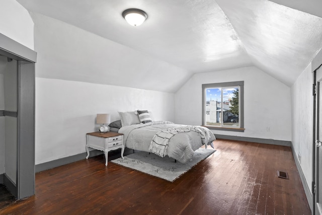 bedroom with lofted ceiling, visible vents, baseboards, and hardwood / wood-style flooring