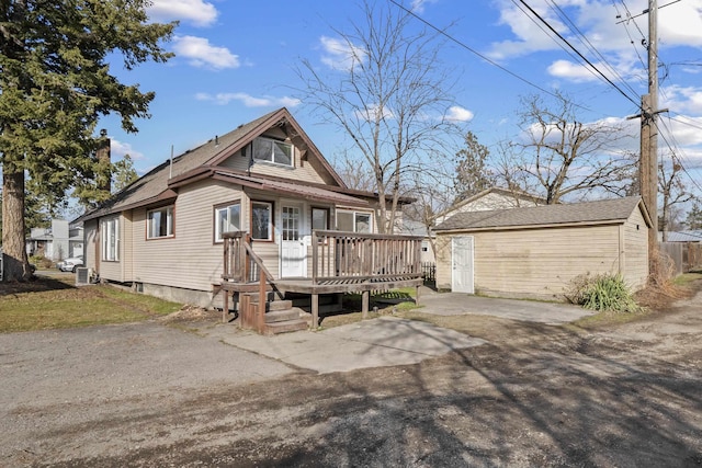 view of front facade with an outbuilding, driveway, and a wooden deck