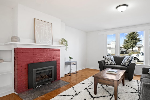 living area with a brick fireplace, wood finished floors, and baseboards