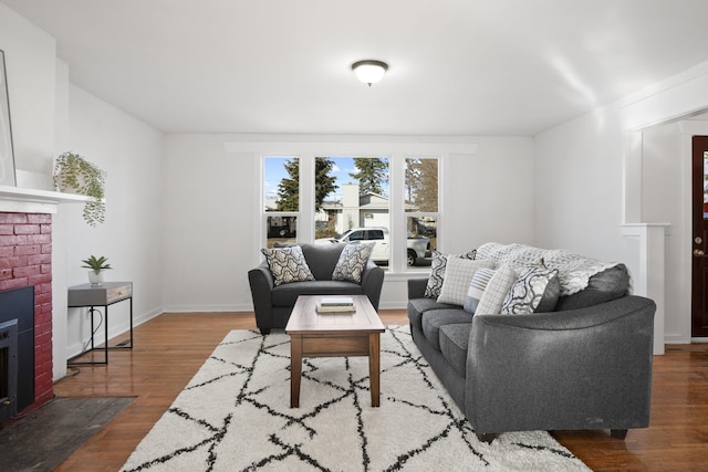 living area featuring a fireplace, baseboards, and wood finished floors