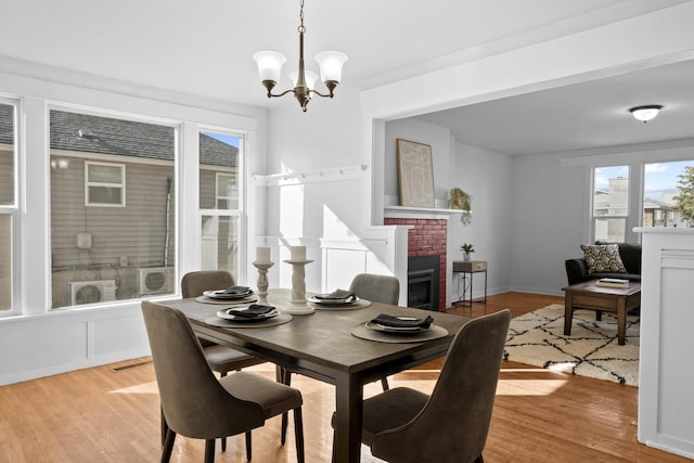 dining room with a notable chandelier, a fireplace, baseboards, and light wood-style floors