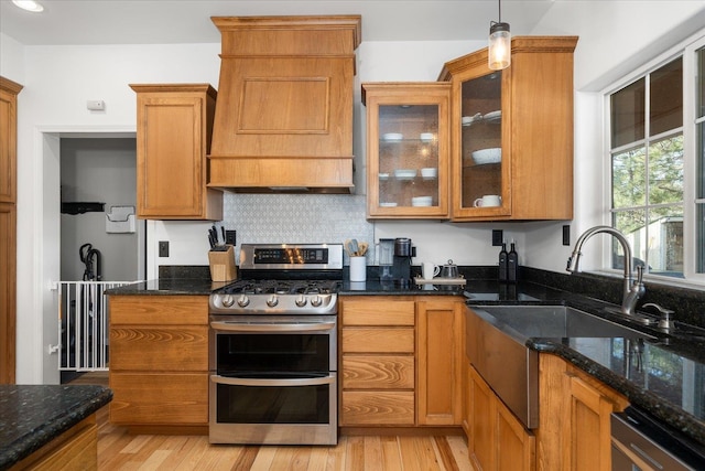 kitchen with light wood-style floors, dark stone counters, double oven range, and custom exhaust hood