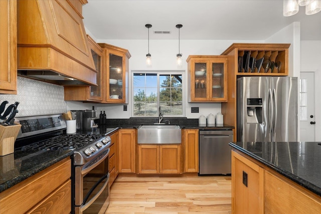 kitchen featuring visible vents, brown cabinets, custom exhaust hood, stainless steel appliances, and a sink