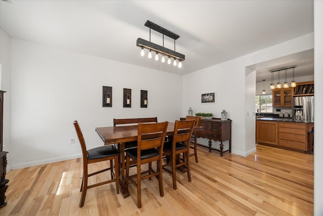 dining space featuring baseboards and light wood finished floors