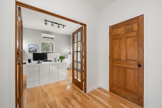 foyer entrance featuring light wood-style floors, track lighting, a wall unit AC, and baseboards