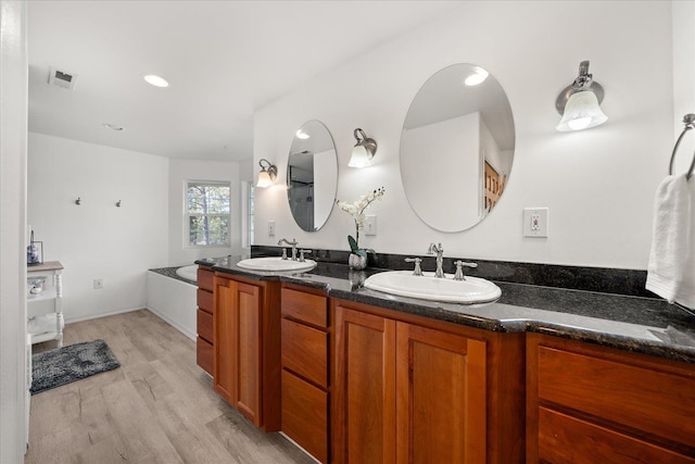 bathroom featuring double vanity, visible vents, a sink, and wood finished floors