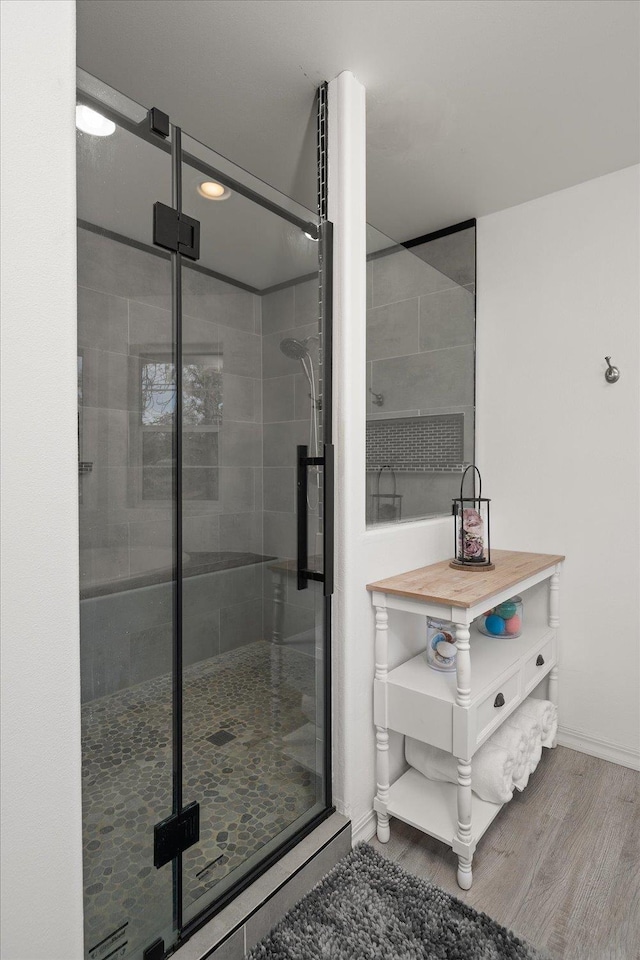 bathroom featuring wood finished floors, a shower stall, and baseboards