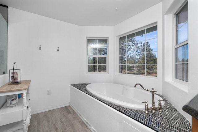 full bath featuring a bath, baseboards, and wood finished floors