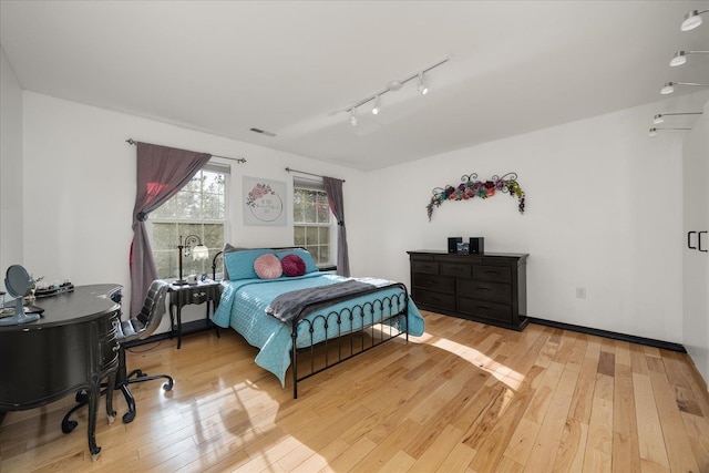 bedroom featuring light wood-type flooring, rail lighting, and visible vents