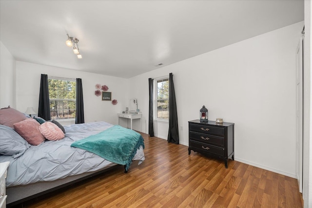 bedroom with light wood finished floors, visible vents, and baseboards