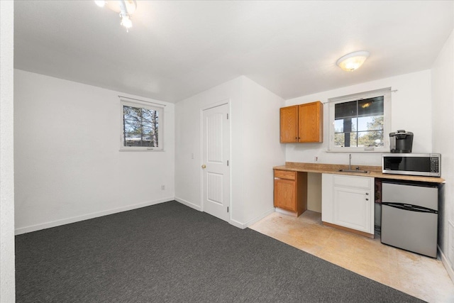 kitchen with plenty of natural light, stainless steel microwave, a sink, and refrigerator