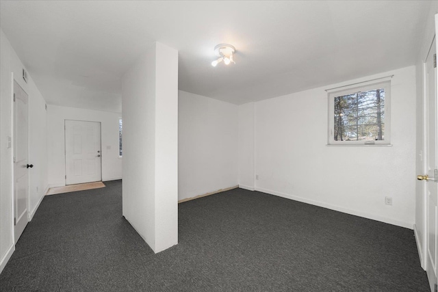 unfurnished room featuring dark colored carpet, visible vents, and baseboards