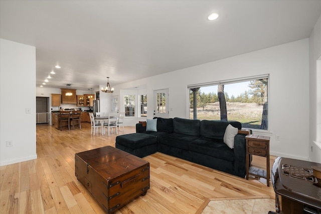 living room with recessed lighting, light wood-type flooring, an inviting chandelier, and baseboards