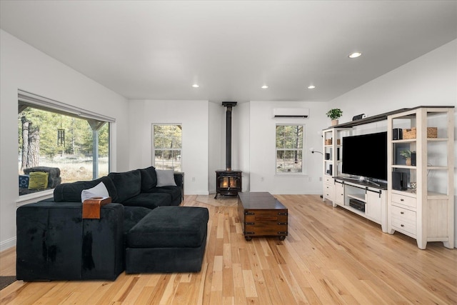 living room with recessed lighting, a wood stove, an AC wall unit, and light wood finished floors