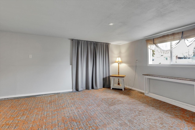 unfurnished room featuring a textured ceiling and baseboards