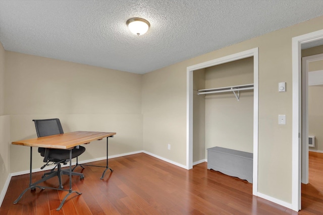 home office with visible vents, a textured ceiling, baseboards, and wood finished floors