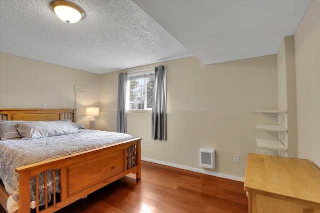 bedroom featuring a textured ceiling, dark wood finished floors, and baseboards