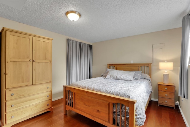 bedroom featuring a textured ceiling, baseboards, and dark wood-style flooring