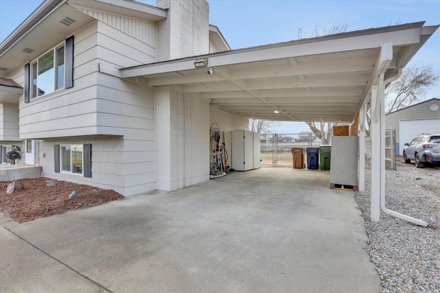 view of vehicle parking with driveway, fence, and a carport