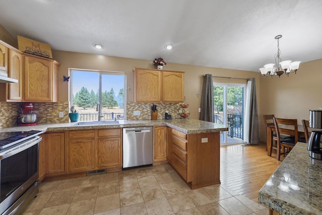 kitchen featuring stainless steel appliances, a peninsula, a sink, visible vents, and decorative backsplash