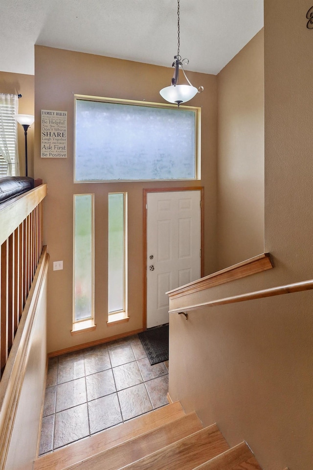 foyer entrance with light tile patterned floors, stairs, and a wealth of natural light