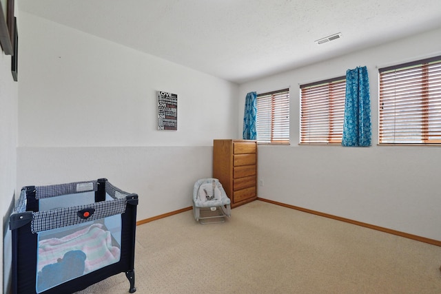 carpeted bedroom with visible vents, baseboards, and a textured ceiling