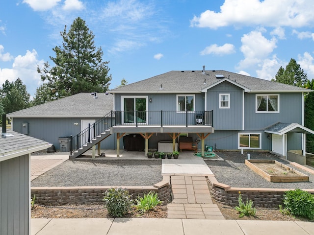 back of house featuring roof with shingles, stairway, a patio area, a deck, and a garden