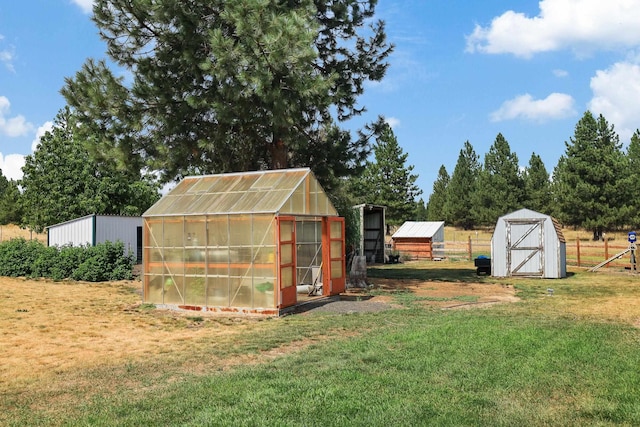 view of greenhouse featuring a yard and a storage unit