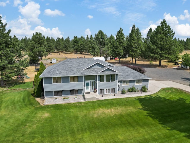 back of property with roof with shingles and a lawn