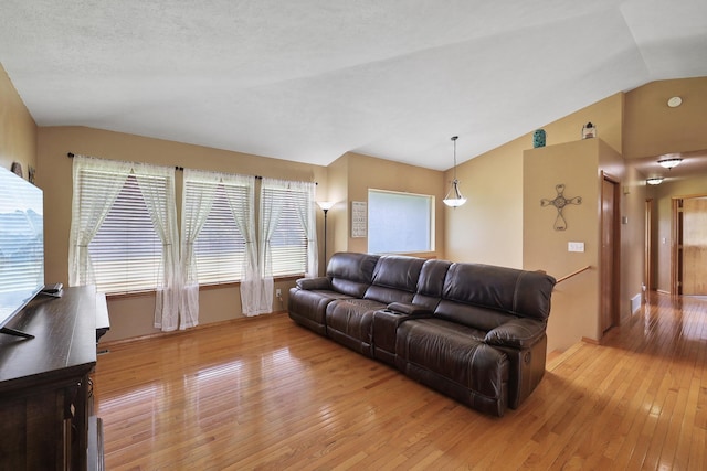 living room with lofted ceiling, light wood finished floors, and a textured ceiling