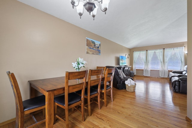 dining room featuring a chandelier, lofted ceiling, and light wood-style flooring