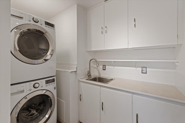 washroom featuring stacked washer and dryer, a sink, and cabinet space