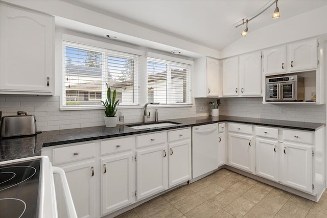 kitchen featuring white dishwasher, white cabinetry, vaulted ceiling, and a sink