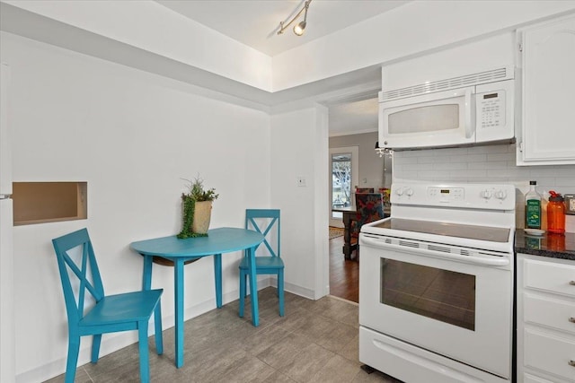 kitchen featuring white appliances, decorative backsplash, dark countertops, crown molding, and white cabinetry