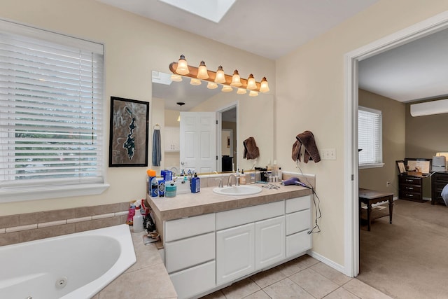 ensuite bathroom with a skylight, vanity, a wealth of natural light, and tile patterned floors