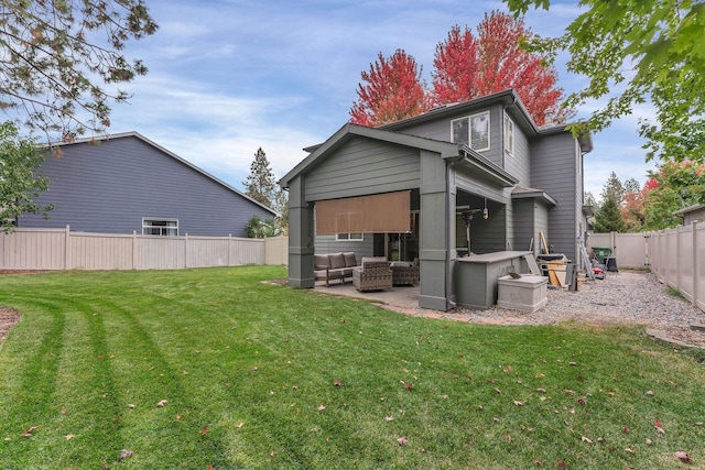 rear view of house featuring a fenced backyard, a yard, a patio, and an outdoor hangout area