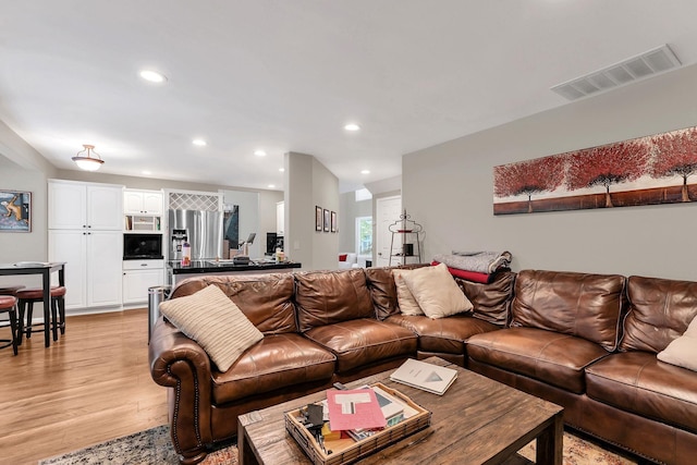 living room featuring light wood-type flooring, visible vents, and recessed lighting