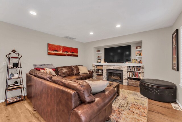 living room featuring light wood-style floors, a fireplace, and visible vents