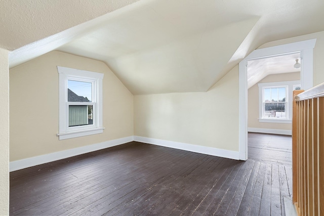 bonus room with dark wood-style flooring, vaulted ceiling, a textured ceiling, and baseboards