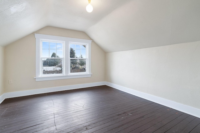 additional living space with lofted ceiling, dark wood-style flooring, a textured ceiling, and baseboards