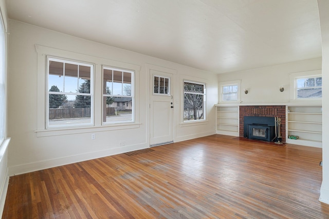 unfurnished living room featuring a wealth of natural light, baseboards, and wood finished floors