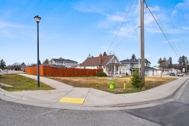 view of front of home featuring a residential view, fence, and a front lawn