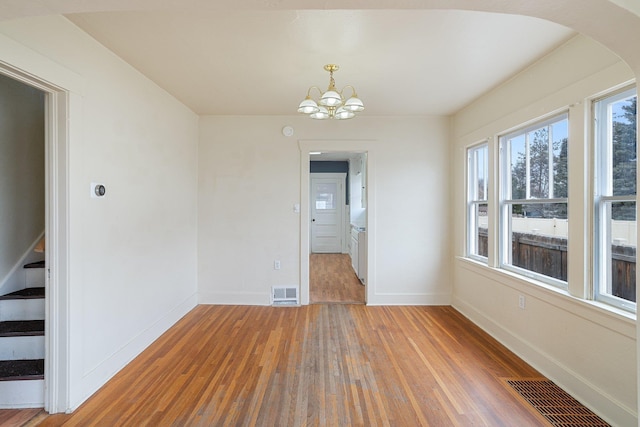 unfurnished room featuring stairway, wood finished floors, visible vents, and baseboards