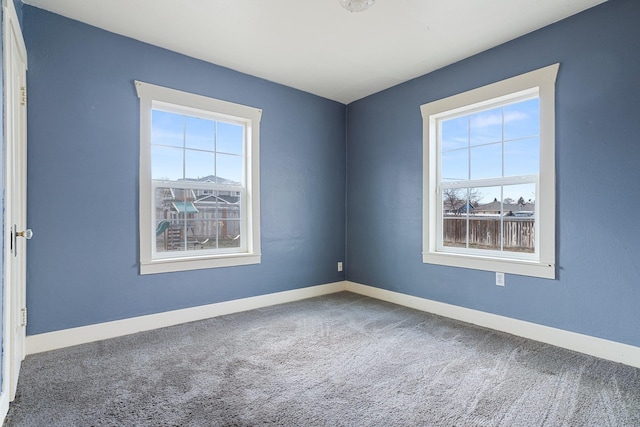 carpeted empty room featuring baseboards