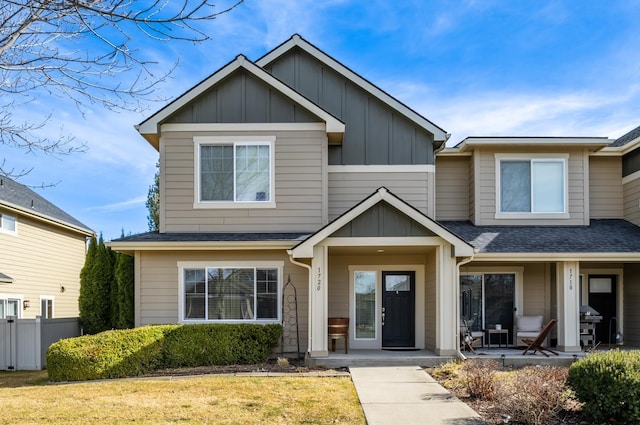 view of front of home featuring roof with shingles, a front lawn, board and batten siding, and fence