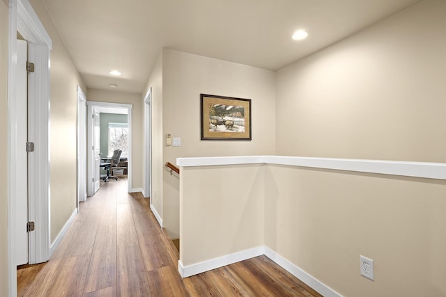 corridor with recessed lighting, baseboards, wood finished floors, and an upstairs landing