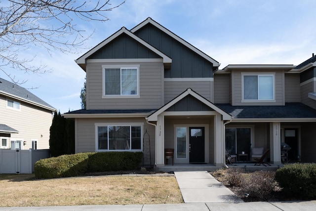 view of front of property with roof with shingles, fence, a front lawn, a porch, and board and batten siding