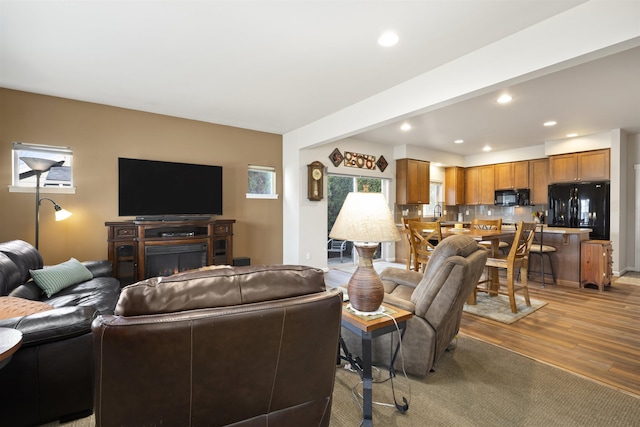 living area featuring light wood finished floors, a lit fireplace, and recessed lighting