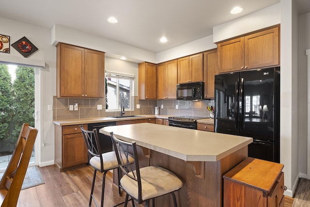 kitchen with black appliances, light countertops, a sink, and brown cabinetry